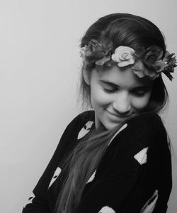 Woman wearing wreath while looking down against white background