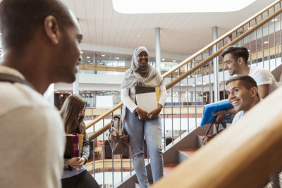 Smiling male and female students discussing on steps