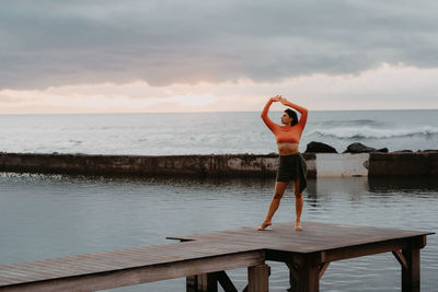 Man standing on pier over sea against sky