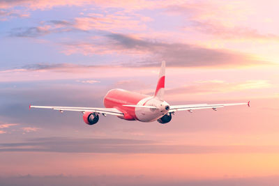 Low angle view of airplane against sky during sunset