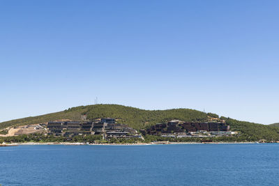 Scenic view of sea by building against clear blue sky