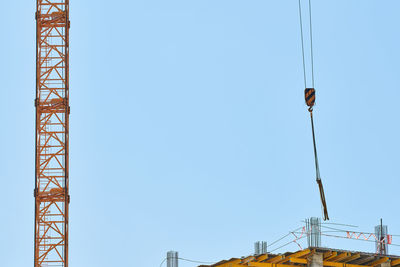Low angle view of crane against clear blue sky