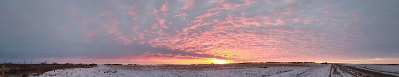 Snow covered road against sky during sunset