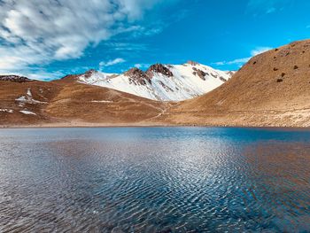 Scenic view of lake and mountains against blue sky