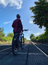 Rear view of woman riding bicycle on railway tracks 