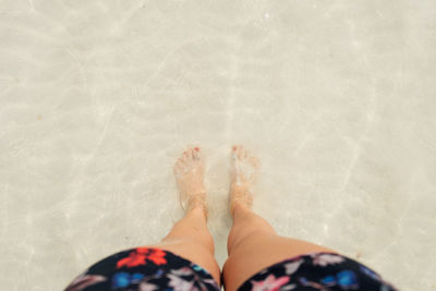 Low section of woman standing in swimming pool