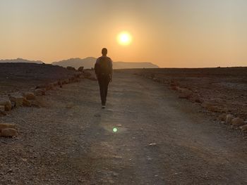 Rear view of man standing on street during sunset