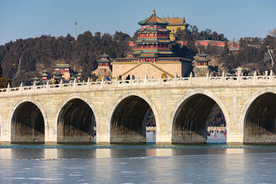 Arch bridge over river against buildings