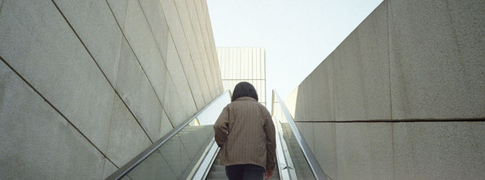 Rear view of woman walking on staircase against building