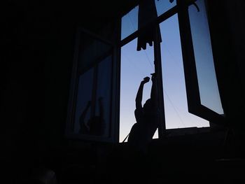 Low angle view of silhouette man against window