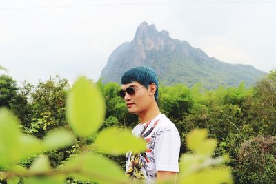 Man wearing sunglasses while standing against mountain