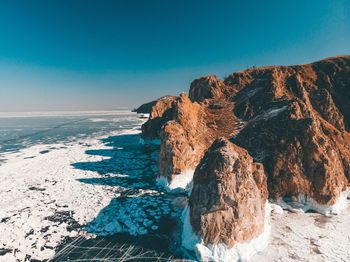 Rock formations in sea against blue sky