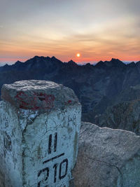 Text on rock against sky during sunset