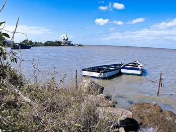 Boats moored in sea against sky