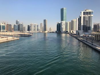 River amidst buildings in city against clear sky