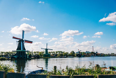 Traditional windmill by river against sky