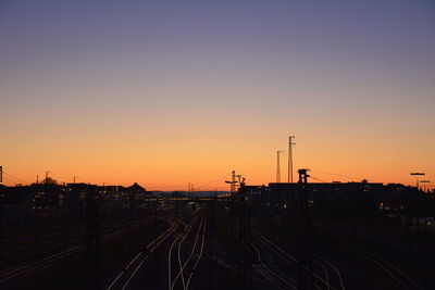 Train on railroad tracks against clear sky during sunset