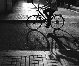 Low section of man riding bicycle on street at night