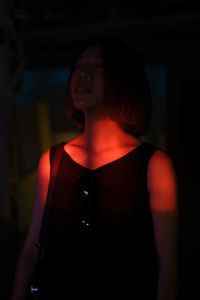 Midsection of woman looking away while standing in illuminated room