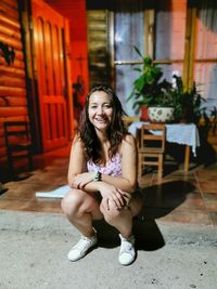 Portrait of smiling young woman sitting at porch