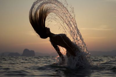 Woman looking at sea against sky during sunset