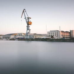 Cranes at harbor against clear sky