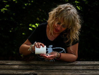 Woman holding medicine while sitting on table outdoors