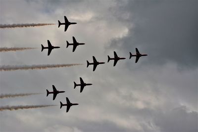 Low angle view of airshow against cloudy sky