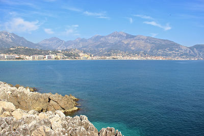 Scenic view of sea and mountains against blue sky