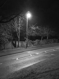 Illuminated road against sky at night