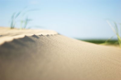 Low section of book on sand at beach against sky