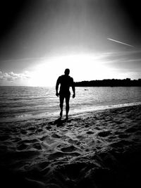 Silhouette man standing on beach against sky during sunset