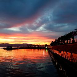 Scenic view of lake against dramatic sky during sunset