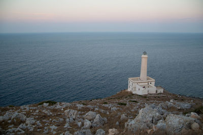 Lighthouse by sea against sky during sunset