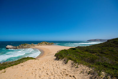 Scenic view of beach against clear blue sky