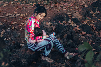 High angle view of mother with baby girl sitting on rock