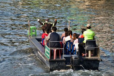 Rear view of people sitting on boat