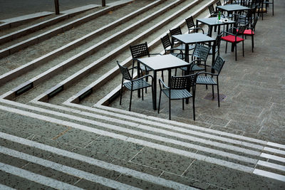 High angle view of empty chairs and tables at sidewalk cafe