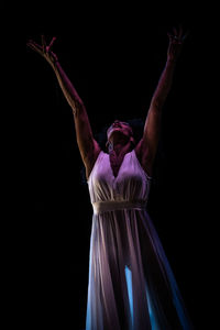 Young woman dancing against black background