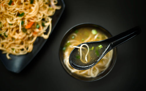 High angle view of soup and noodles over black background