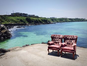 Empty chairs at beach against clear sky