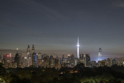 Illuminated buildings in city against sky at night