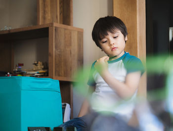 Cute boy holding toy sitting at home