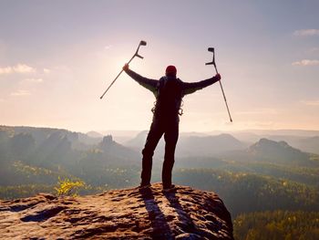 Rear view of man standing on mountain against sky