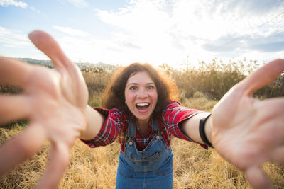 Portrait of smiling young woman standing on field against sky