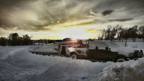 Snow covered landscape against sky during sunset