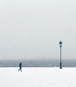 Man standing on snow covered landscape against sky