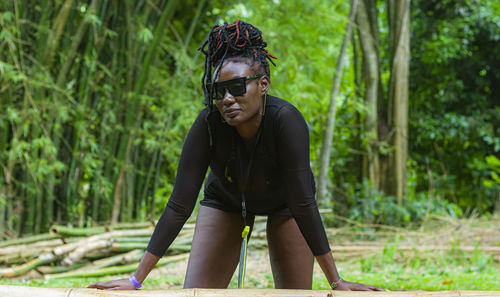 Portrait of young woman wearing sunglasses while standing in forest