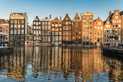 Canal by buildings against sky in city