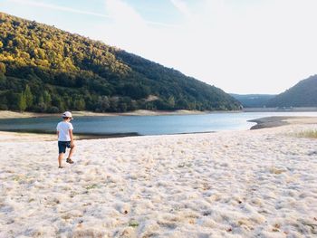 Rear view of boy walking on sand at beach